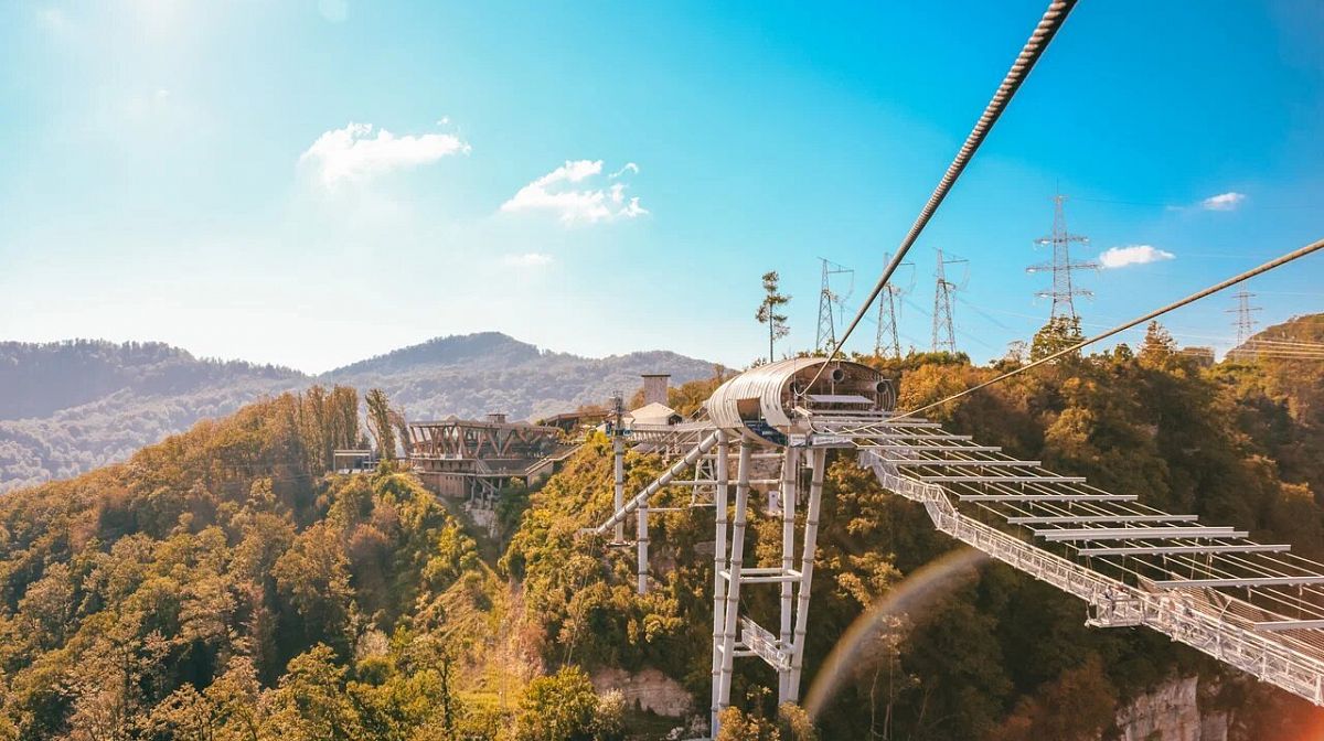 Мост Skybridge и трос Zipline над лесистым Ахштырским ущельем в солнечный день