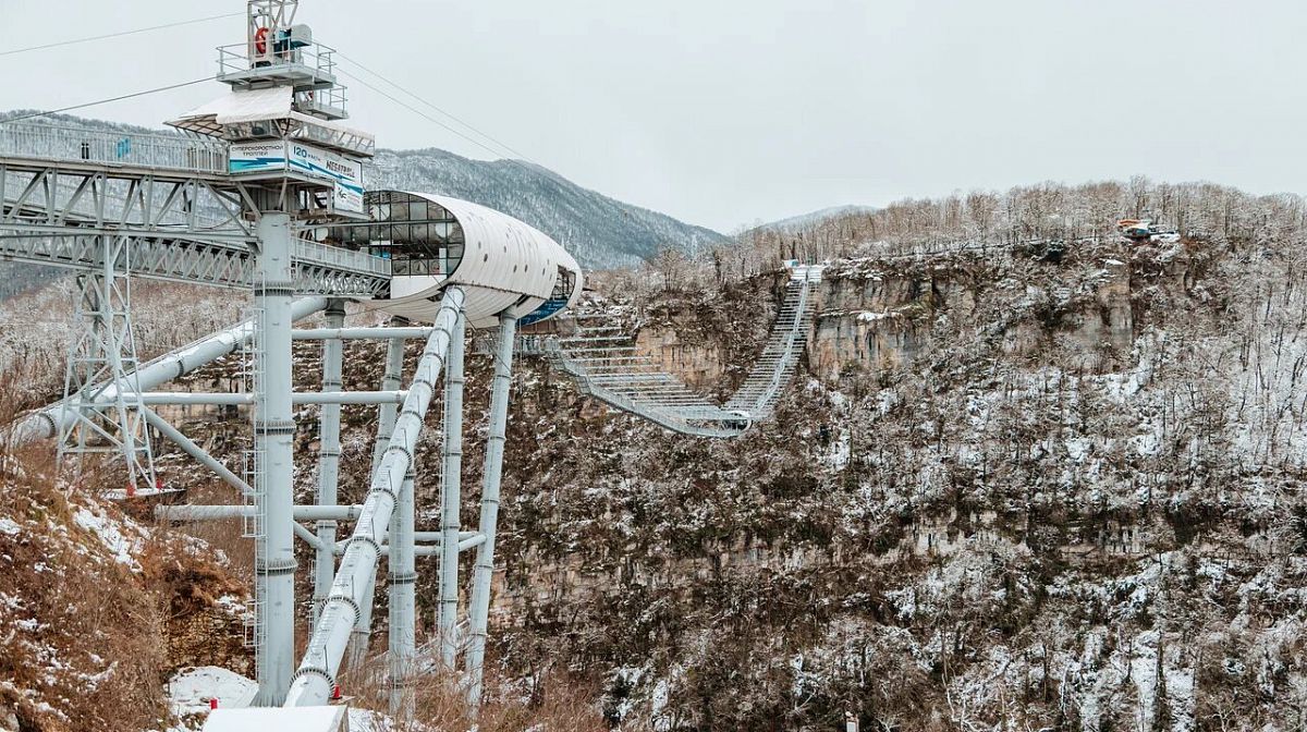 Мост Skybridge и капсула над заснеженным Ахштырским ущельем в пасмурный зимний день