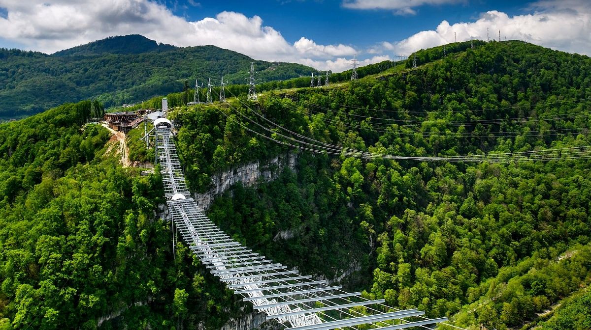 Подвесной мост Skybridge тянется над лесистым Ахштырским ущельем, вид сверху в солнечный день